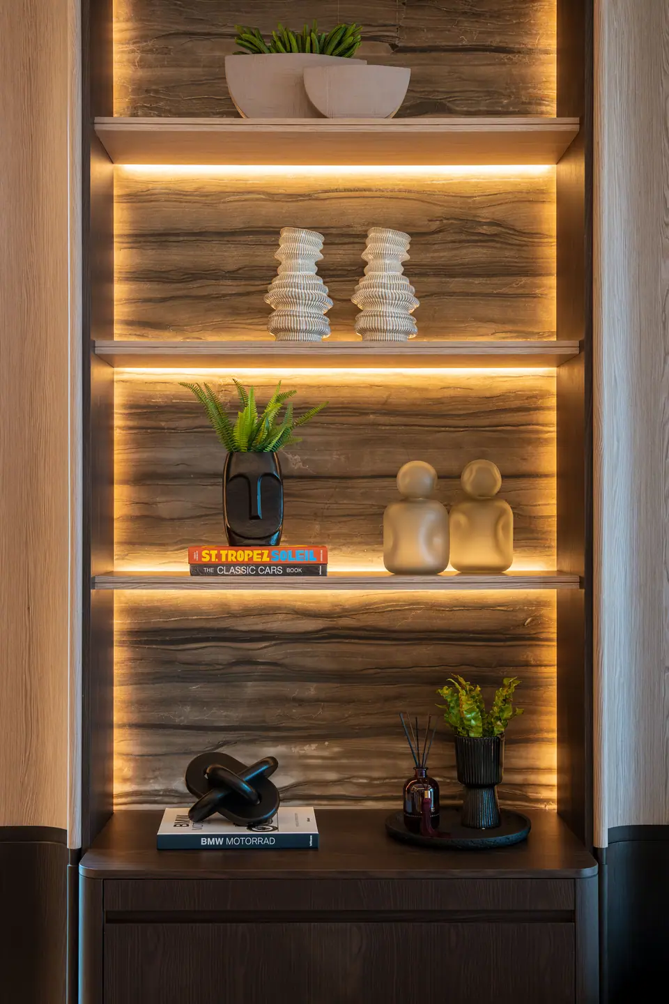 B.C.A. Kempinski Residences — Ahşap desenli fonlu ve koyu seramikli aydınlatmalı raflar