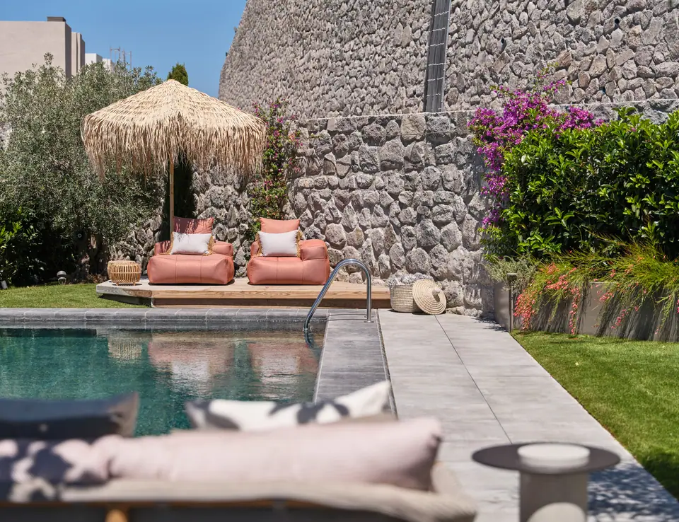G.Ç. The One Bodrum — Hasır şemsiyeli ve taş duvarlı bahçe havuzu